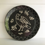 Black Plate with white dotted drawing of a bird